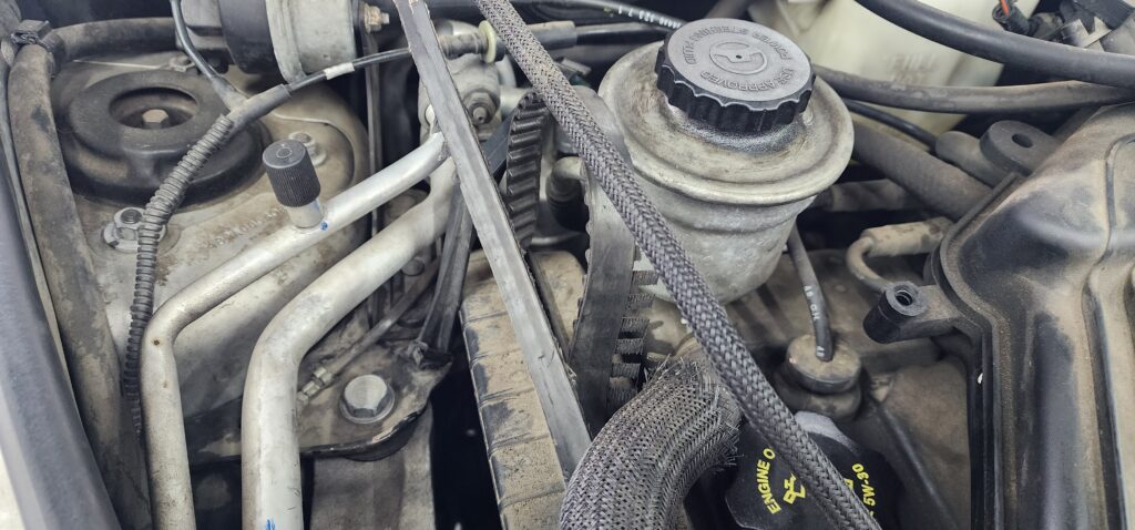Close-up of a worn timing belt in a car engine, showing cracks and fraying, needing replacement in Kennewick, WA 99336.